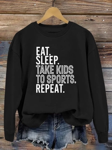 Gros plan du slogan blanc imprimé sur un sweat noir à col rond contre un mur en bois