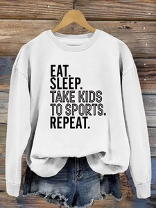 Gros plan du slogan Eat Sleep Take Kids To Sports imprimé sur un sweat blanc à manches longues