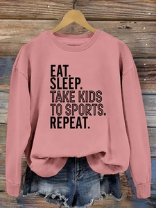 Détail du slogan Eat Sleep Take Kids To Sports sur un sweat-shirt rose poudré
