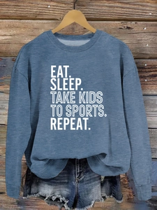 Détail de l'imprimé Eat Sleep Take Kids sur un sweat-shirt bleu avec cintre en bois