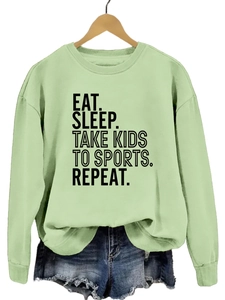 Détail du col rond et de l'imprimé texte noir sur le sweat-shirt vert clair