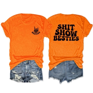 Detailed flat lay of bright orange t-shirt with Shit Show Besties print and denim shorts