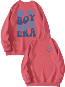 Close-up of pink crewneck sweatshirt with 'Boy Mom Era' text and smiley face print