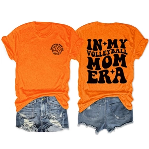 Detail von In My Volleyball Mom Era Print auf orangefarbenem Shirt mit Jeansshorts