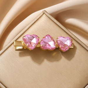 Elegante pinza para el pelo de metal dorado con tres cristales de corazón rosa en satén