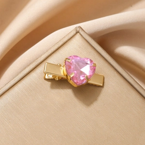 Pinza de pelo con corazón rosa y acabado dorado sobre elegante seda color champán