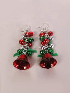 Detail of Christmas star bell earrings with green ribbon bow and red metallic pendants