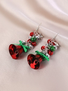 Detail of Christmas earrings featuring red bells, green bows, and silver stars charms