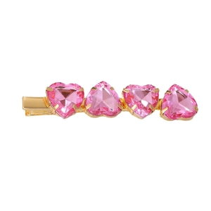 Pasador de pelo dorado con cuatro gemas rosas en forma de corazón sobre fondo blanco