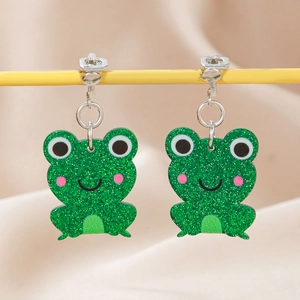 Detail of green glitter frog clip-on earrings for kids on a yellow display stand