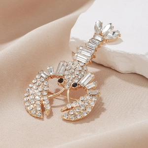 Exaggerated gold-tone lobster brooch with sparkling crystals on elegant silk background