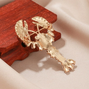 Golden lobster brooch in alloy metal with sparkling rhinestone accents on satin fabric
