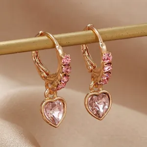 Boucles d'oreilles cœur élégantes avec zircons roses et alliage doré sur fond de velours