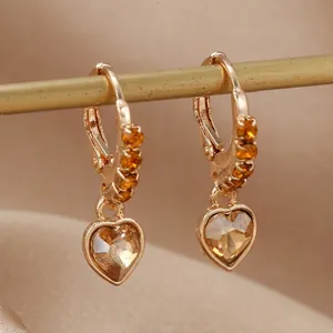 Vue détaillée de boucles d'oreilles cœur dorées avec cristaux ambrés sur tissu de soie