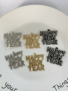 Macro shot of rhinestone HAPPY NEW YEAR pendants in gold, silver, and black metal finish