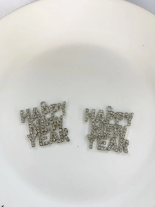 Macro detail of silver Happy New Year charms with sparkling rhinestones for DIY jewelry
