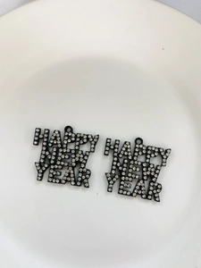 Close-up of Happy New Year black alloy charms with inlaid rhinestones for DIY jewelry