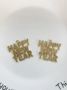 Close-up of gold plated Happy New Year charm pendants with white rhinestones