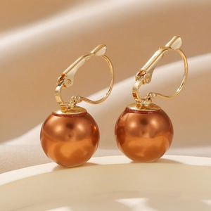 Detailansicht eleganter goldener Brisur-Ohrringe mit glänzenden braunen Perlenperlen