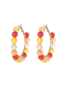 Macro detail of gold hoop earrings with red, yellow, and orange matte plastic beads