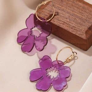 Elegant purple acrylic flower hoop earrings with gold-tone rings on textured display