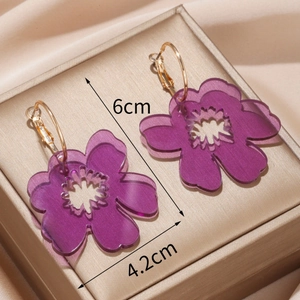 Fashionable purple acrylic flower earrings with gold metal hoops on jewelry box
