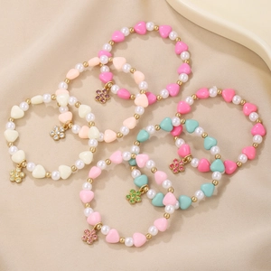 Detailed close-up of five beaded heart and flower charm bracelets for young girls
