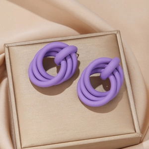 Macro detail of purple matte twisted knot earrings on champagne satin background
