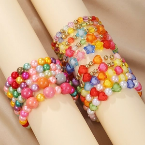 Detail of colorful beaded heart and star bracelets on cream cylinder display stands