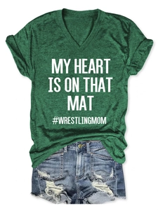 Detail of dark green V-neck T-shirt with white lettering and ripped denim shorts