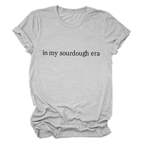 Detailed view of 'in my sourdough era' black text print on a grey cotton t-shirt
