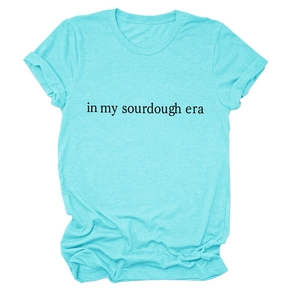 Close-up of the 'in my sourdough era' text print on a teal cotton crewneck t-shirt