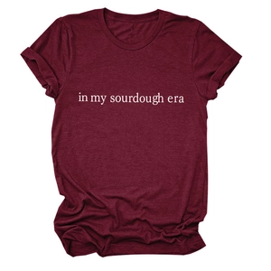 Close-up of 'in my sourdough era' white text print on a burgundy crew neck cotton t-shirt