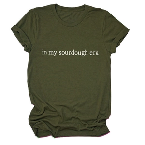 Detailed close-up of olive green t-shirt featuring in my sourdough era white text