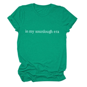 Close-up of 'in my sourdough era' white text print on deep green cotton t-shirt fabric