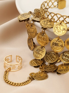 Close-up of gold coin pendants and star cutout ring on bohemian hand chain jewelry