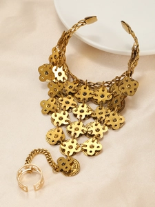 Macro shot of vintage gold floral slave bracelet with coin charms on satin