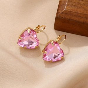 Boucles d'oreilles cœur en cristal rose avec crochets dorés sur fond de soie
