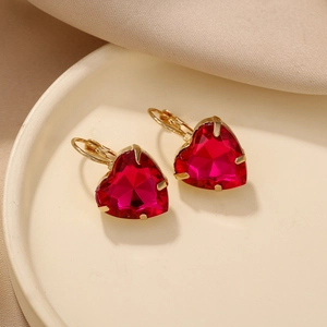 Détail macro de boucles d'oreilles cœur en cristal rouge rubis avec monture dorée