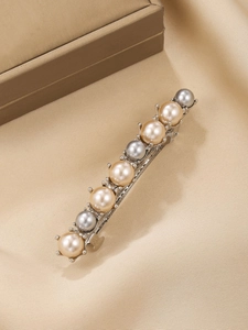 Detail of silver alloy hair clip with champagne and grey pearls on silk fabric