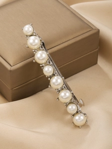 Detail of elegant silver hair clip with eight pearls on gold jewelry box and beige silk