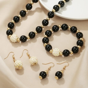 Handmade black beaded jewelry set including long necklace, bracelet and earrings with gold accents