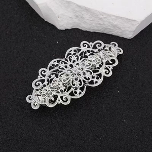 Vintage zilveren metalen haarklem met barok patroon op witte steen en zwart zand
