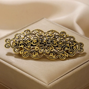 Detail van vintage gouden metalen haarklem met bloemenpatroon op een zijden ondergrond