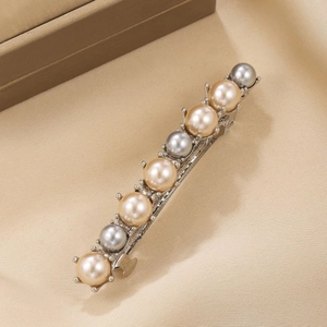 Elegant silver alloy barrette with champagne and grey pearls on a luxury fabric background