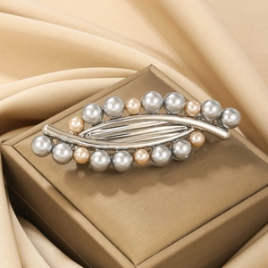 Elegant silver leaf hair clip with champagne and grey pearls on silk background