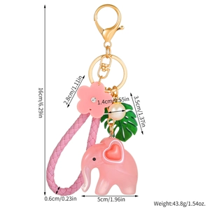 Pink resin elephant keychain with gold clasp, woven strap and charms details