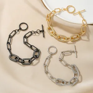 Detailed close-up of oval link bracelets with pavé zircons and toggle clasp on silk