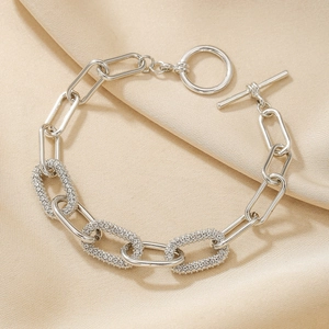 Elegant silver oval link bracelet with diamond inlay on champagne silk background
