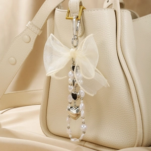 Porte-clés avec nœud en dentelle, perles et cœurs sur un sac en cuir crème